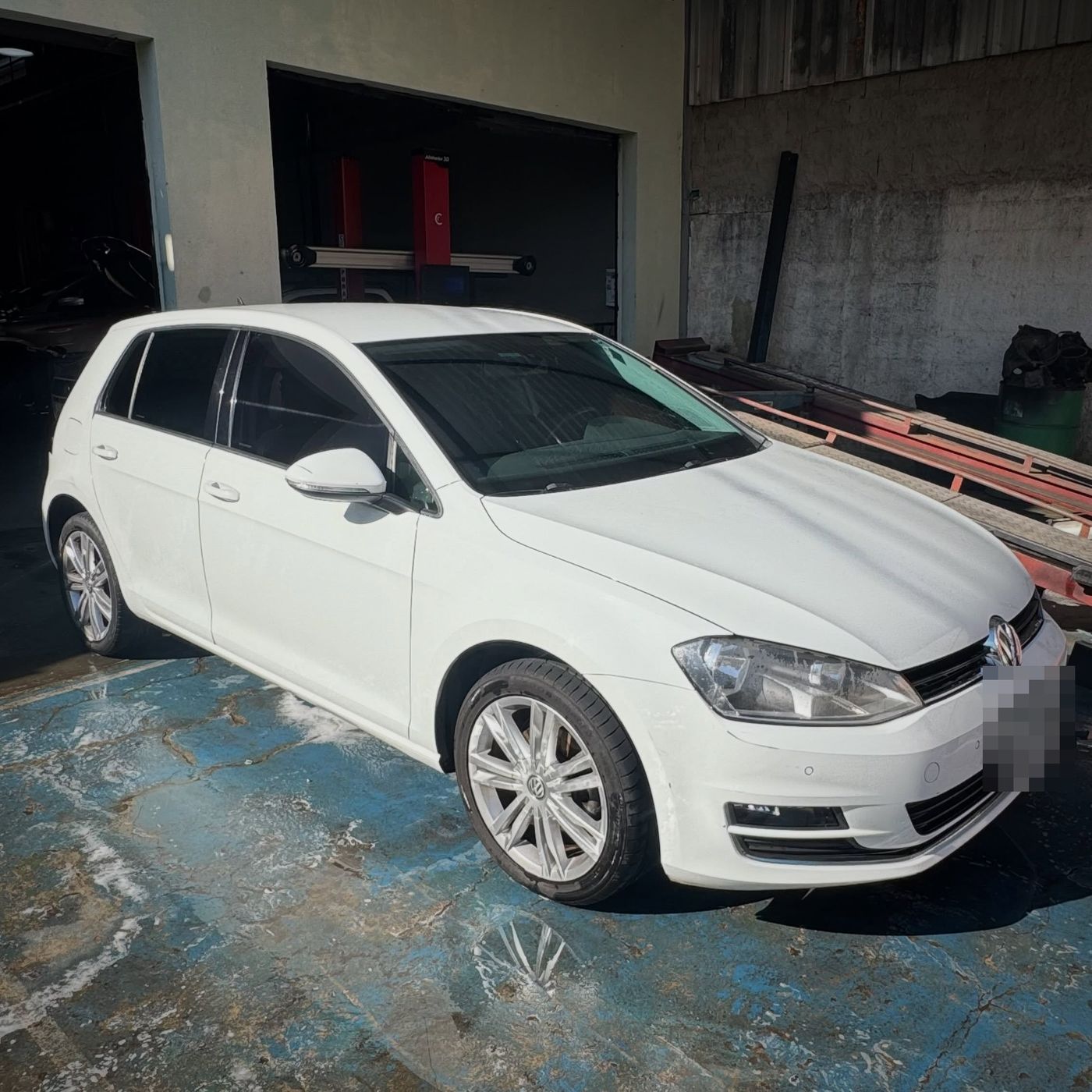 VW Golf branco no pátio em frente aos boxes da oficina